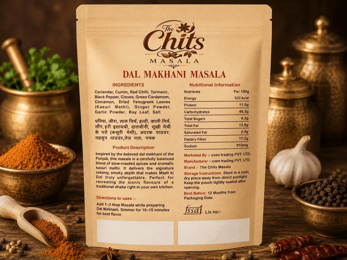 A stand-up pouch of Chits Masala Dal Makhani Masala shown from the back, with product details, ingredients, and directions printed on a beige kraft-style label. The pouch is photographed in a warm, styled setting with spices and kitchen utensils in the background.
