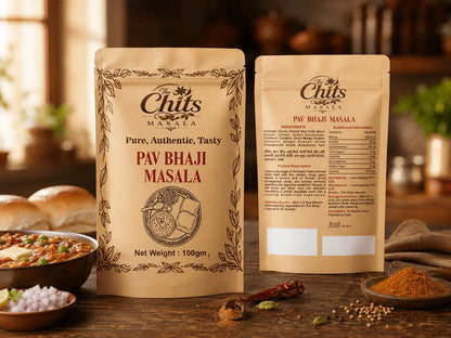 Two stand-up pouches of Chits Masala Pav Bhaji Masala seasoning displayed on a rustic wooden table with food props like bread, onions, and spices in a warm kitchen setting.