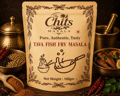 A stand-up pouch of The Chits Masala Tava Fish Fry Masala spice mix, displayed on a rustic wooden table surrounded by ingredients like whole spices, red chilies, and cooked fish in brass vessels.